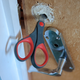 Some scissors poking out of a bathroom door, the door handle unscrewed and dangling below.